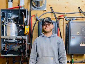 A photo of the owner Remington smiling in front of a boiler
