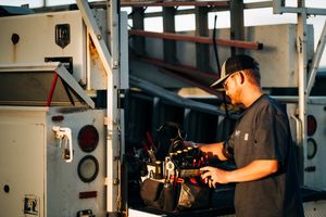 A profile shot of owner Remington standing in front of his work truck pulling out some tools